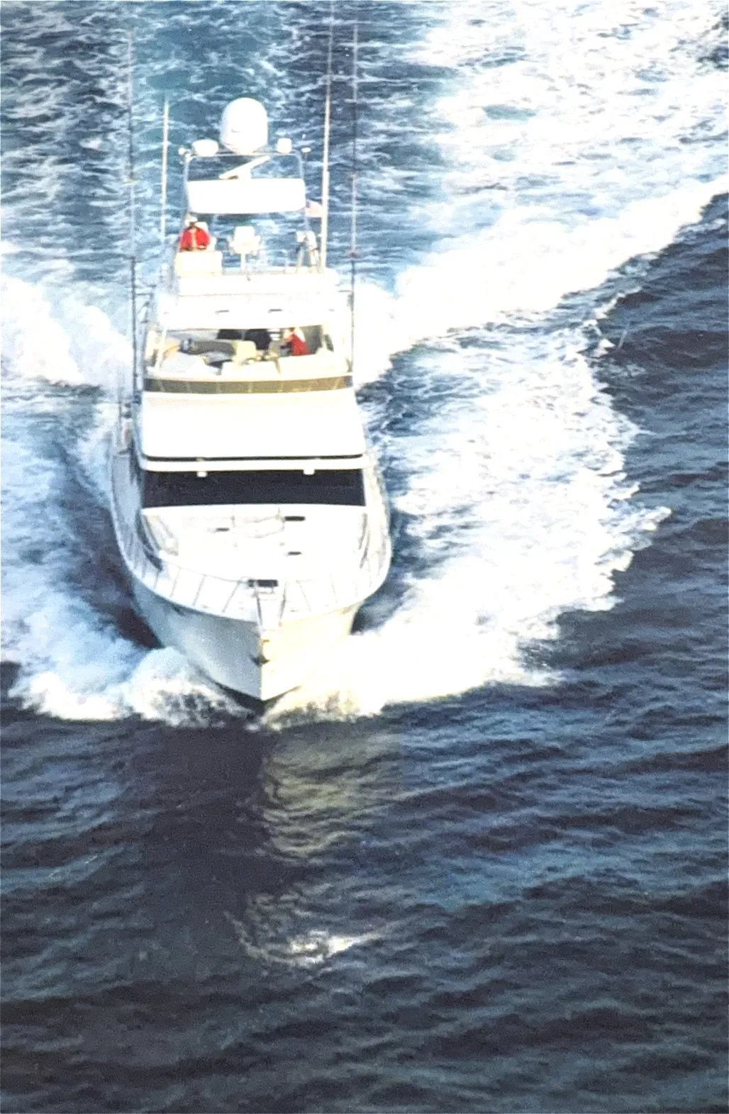 A sportfisher running head on, throwing spray from the bow