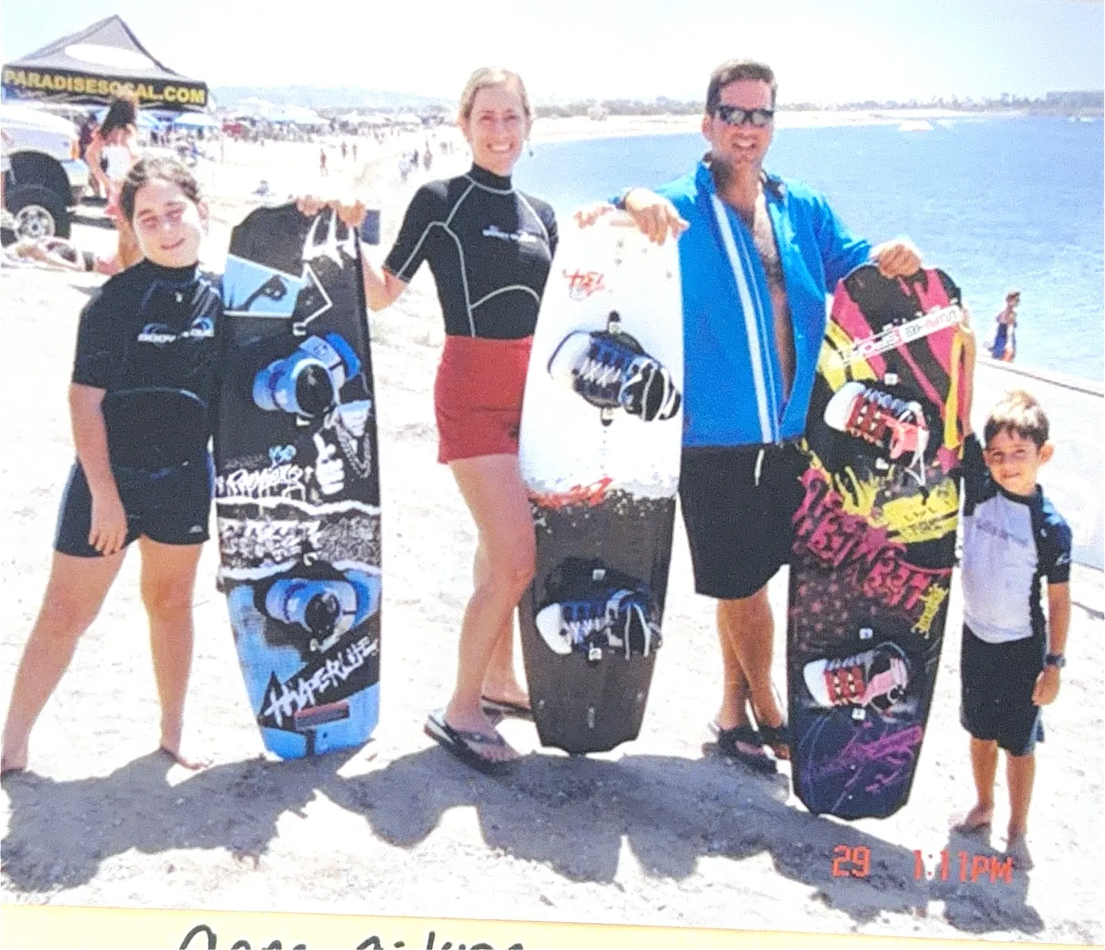 The family on the beach holding wakeboards in front of a branded tent