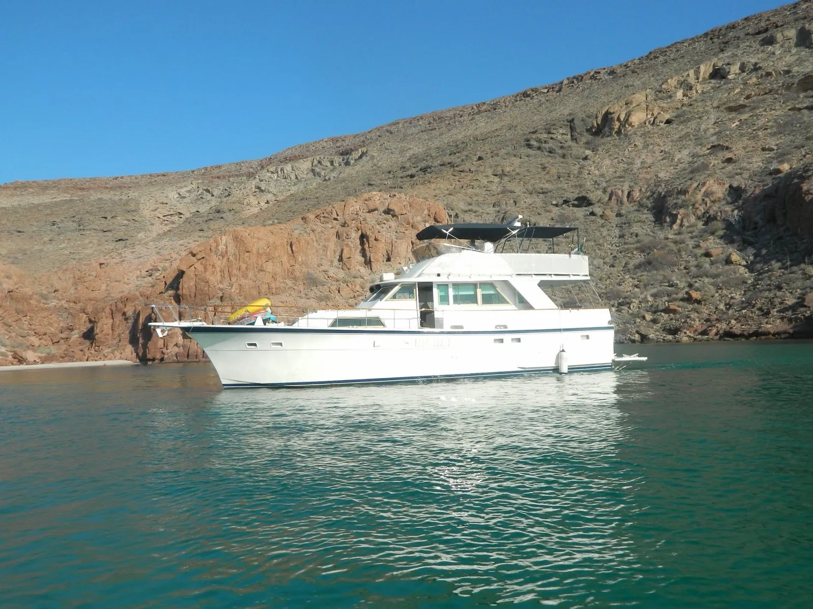 Angeli, a 1979 Hatteras motor yacht, at anchor below red rock cliffs
