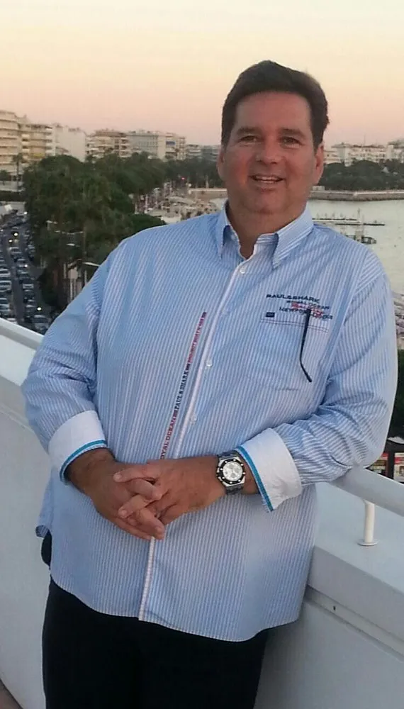 Augusto Otaduy Sr., founder of Otaduy Yachts, on a balcony above a Mediterranean waterfront at dusk