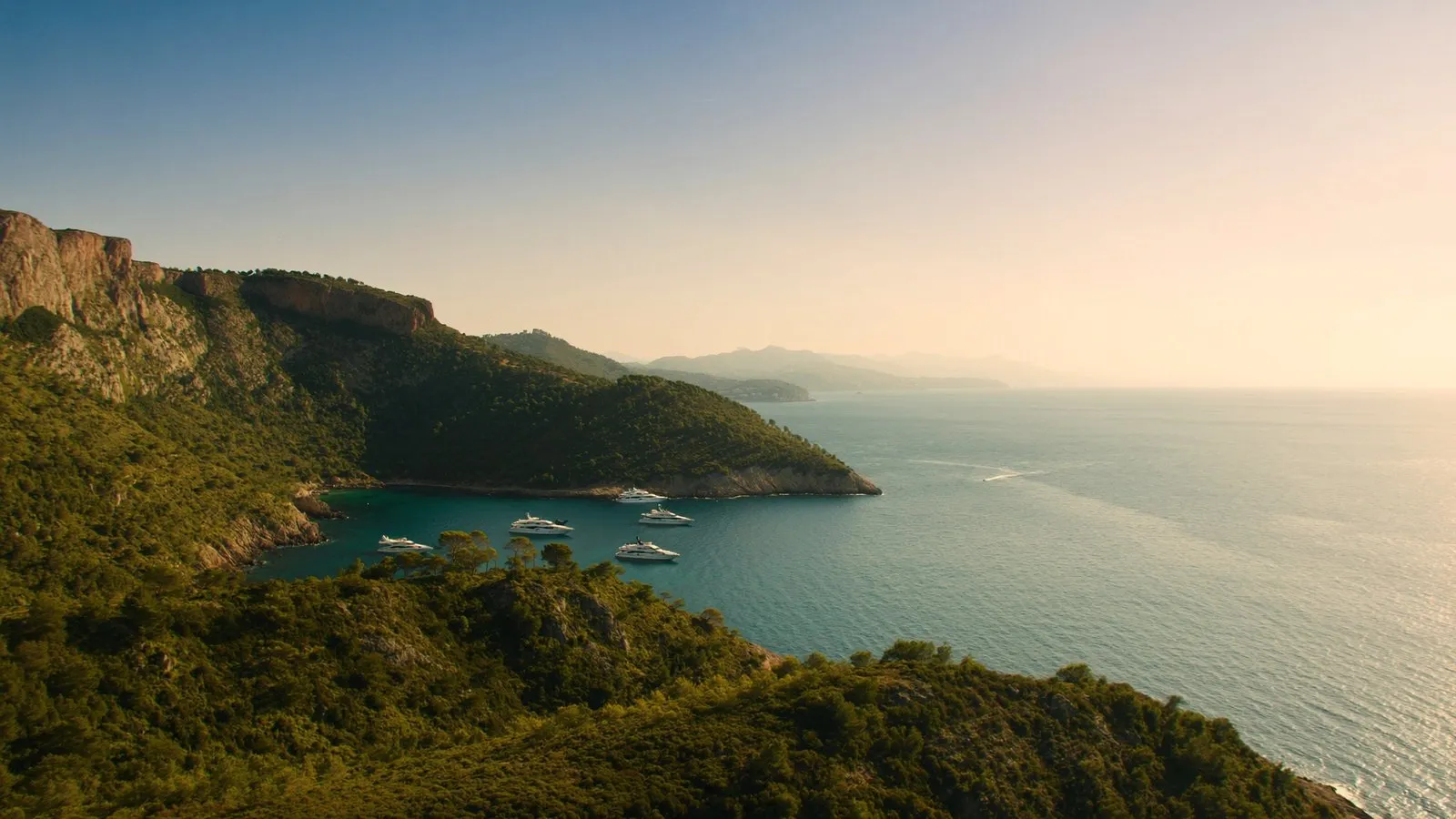 The French Riviera coastline with yachts anchored in a turquoise cove in September light
