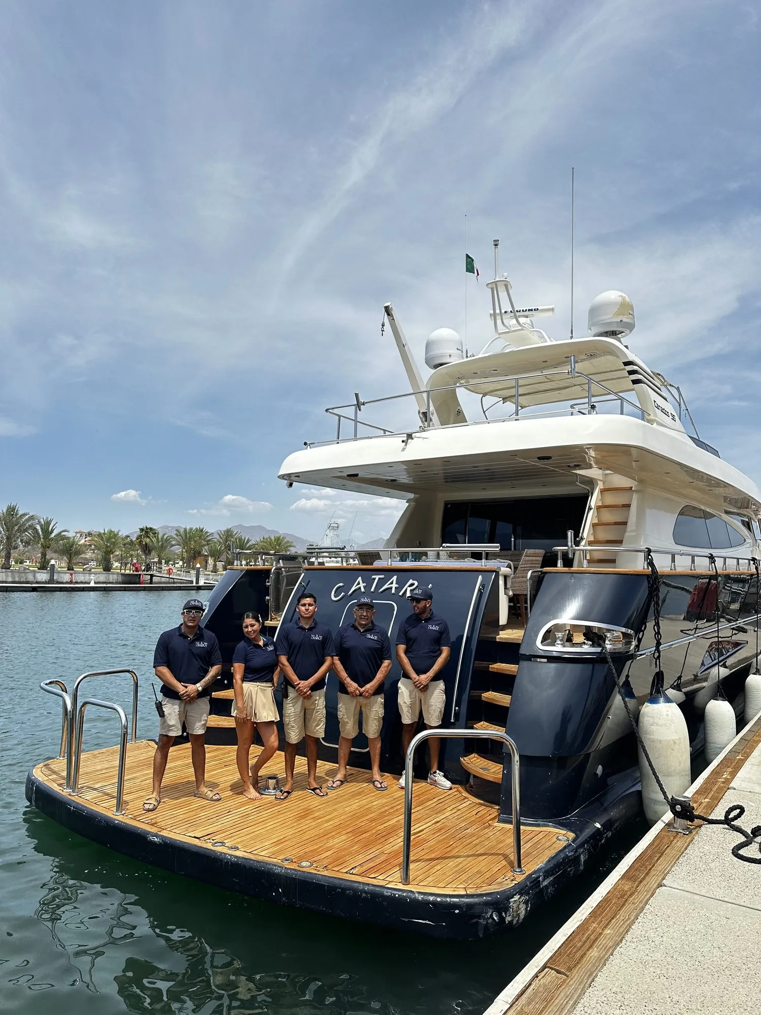 Otaduy crew members standing on the swim platform of a yacht at the marina