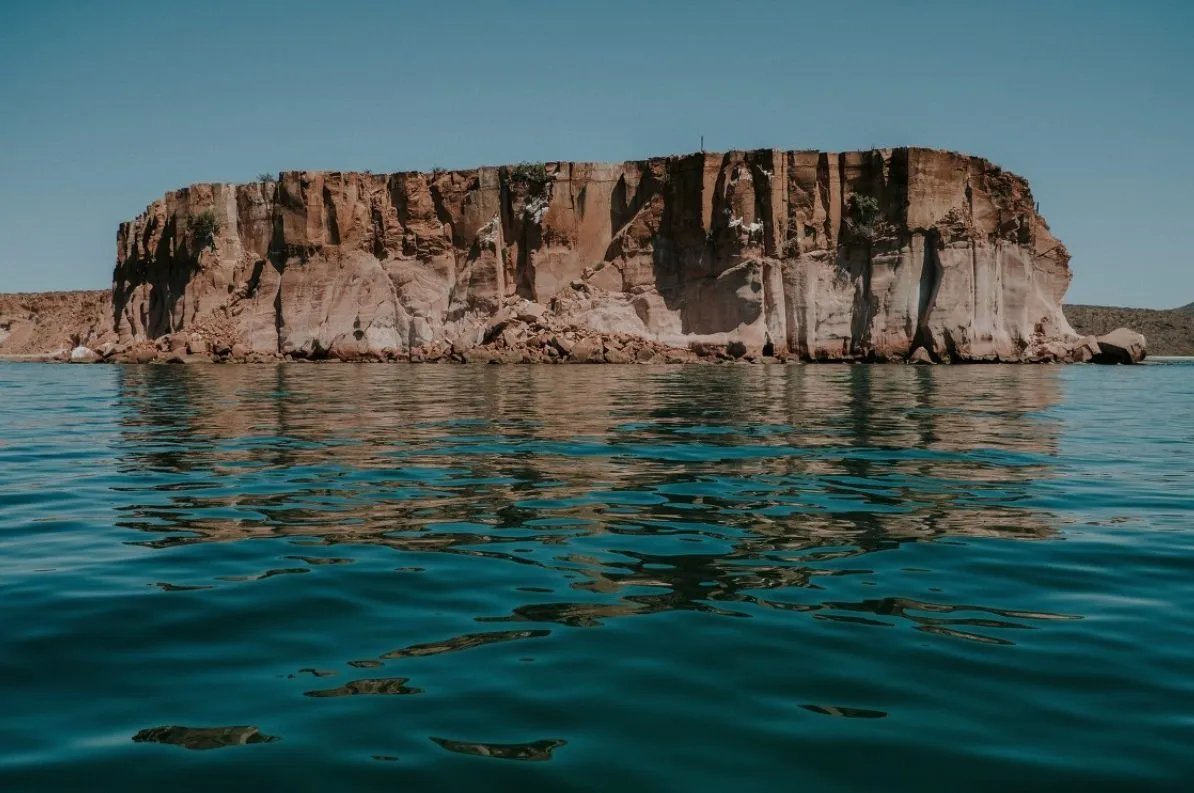 Rock cliffs of Espíritu Santo island rising from clear water