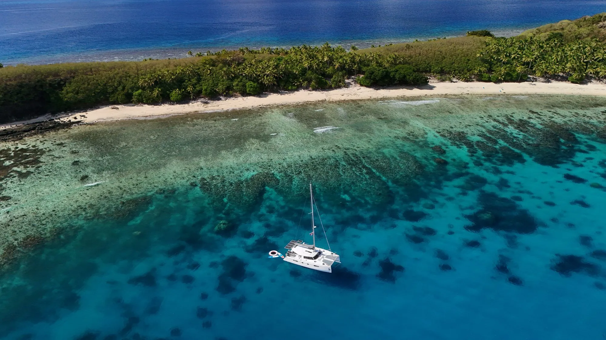Aerial view of Telemachus anchored over a reef beside an island beach