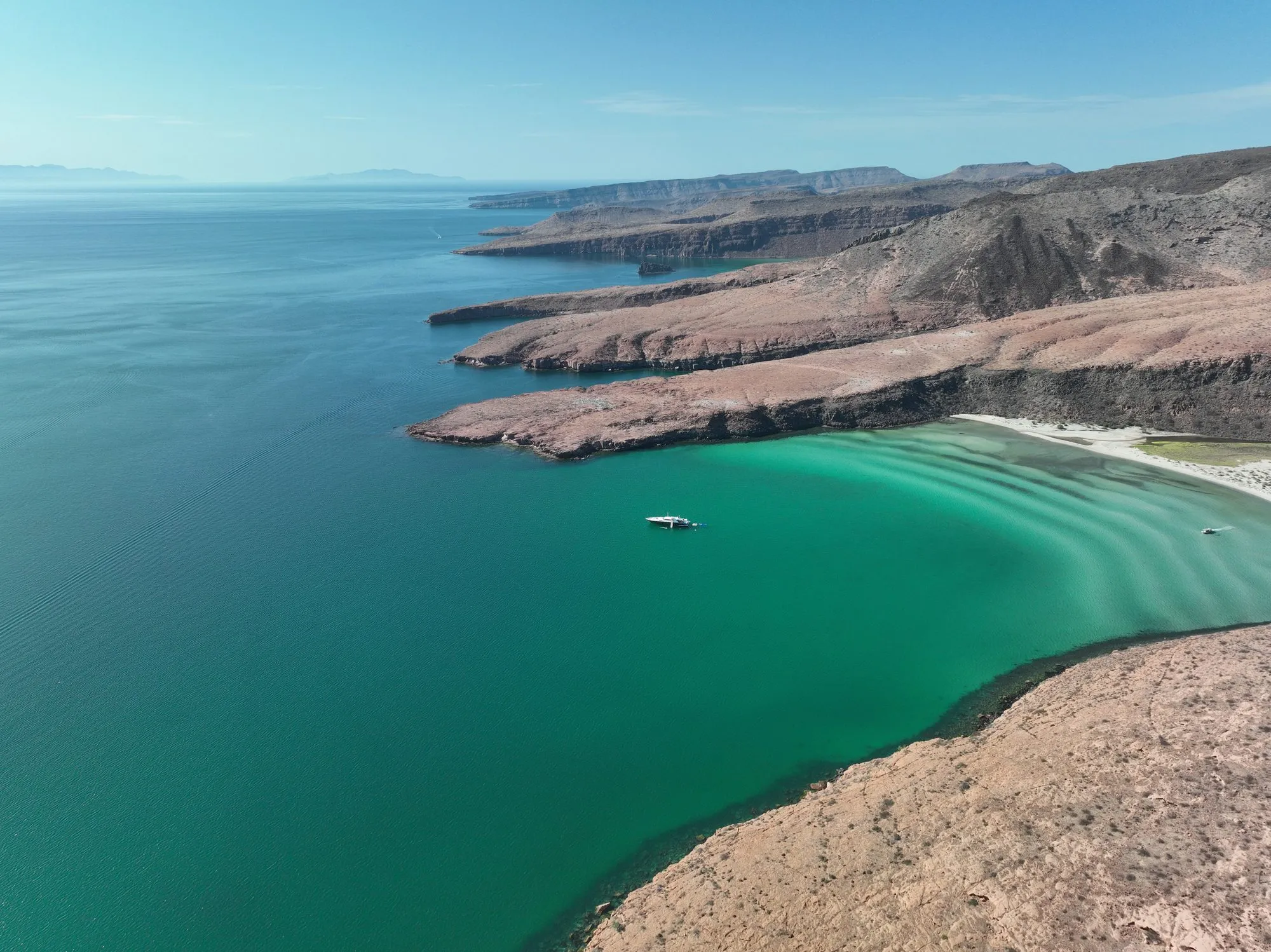 Aerial view of a turquoise cove in Baja California with GO at anchor