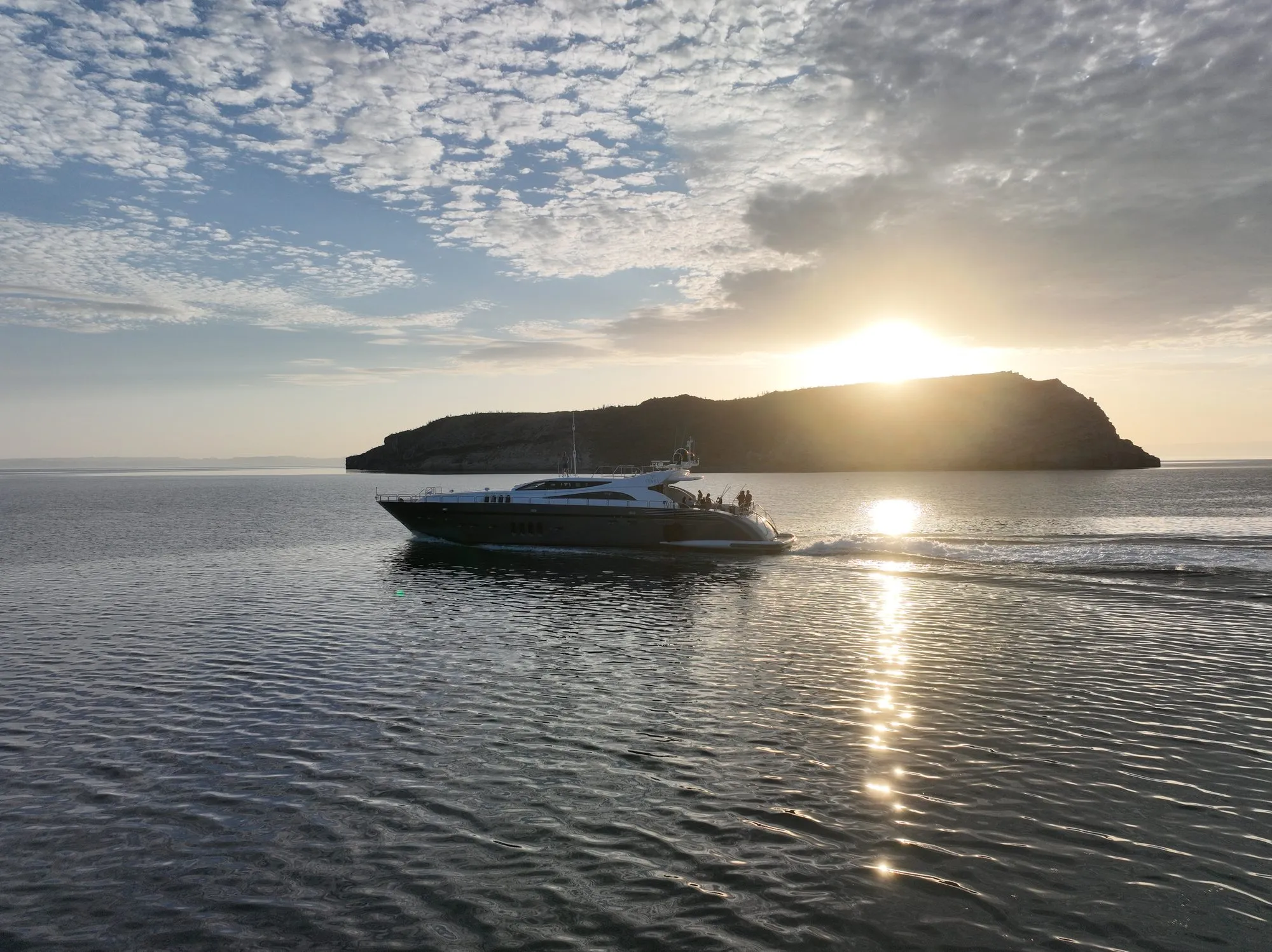 GO cruising past an island at sunset, aerial view