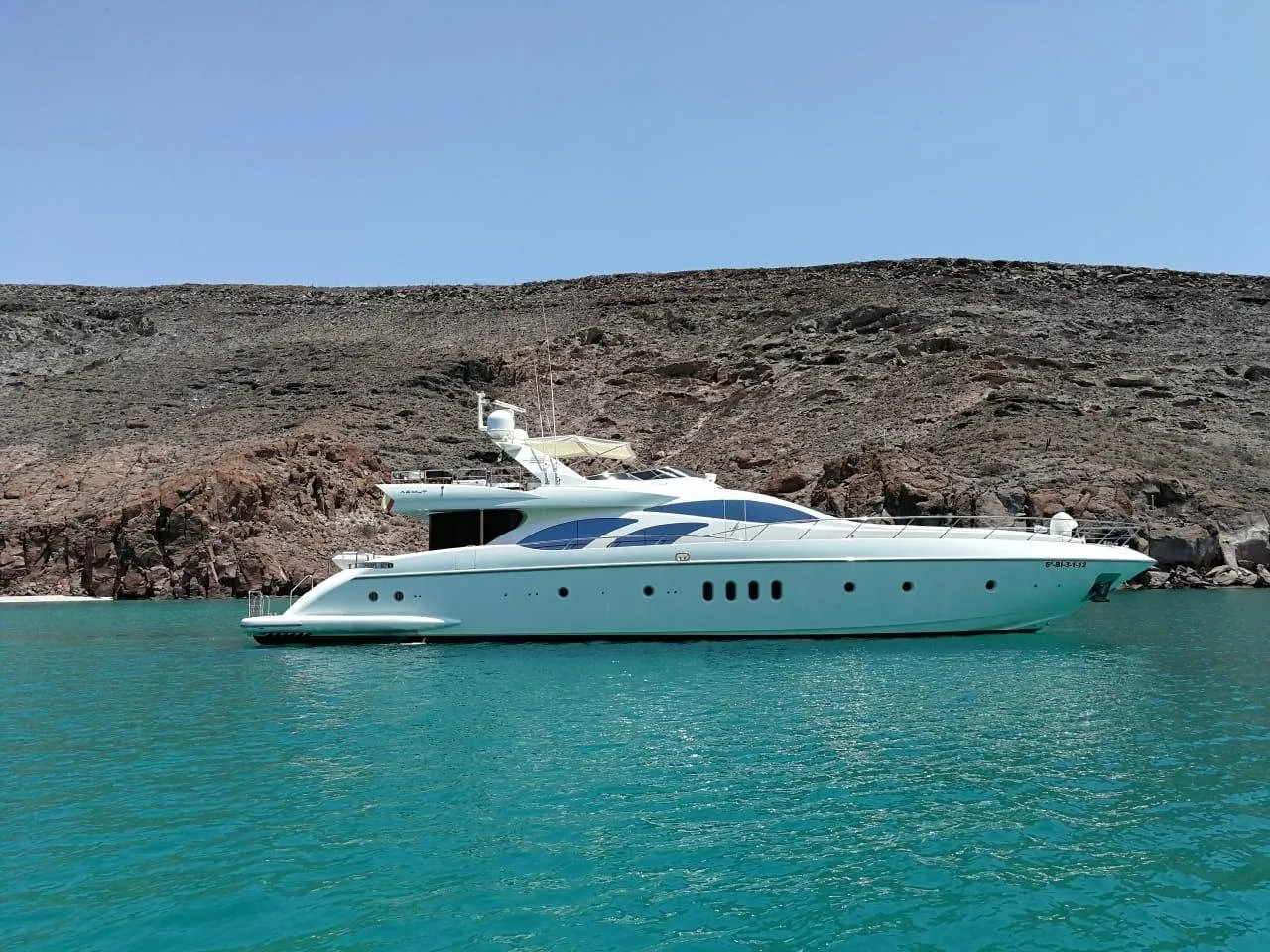 Ganesha, an Azimut 98, at anchor in a cove below desert cliffs