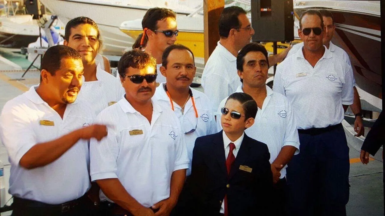 Gus Otaduy at seven years old, in a blazer and tie with his own name badge, standing in line with the Otaduy crew in uniform