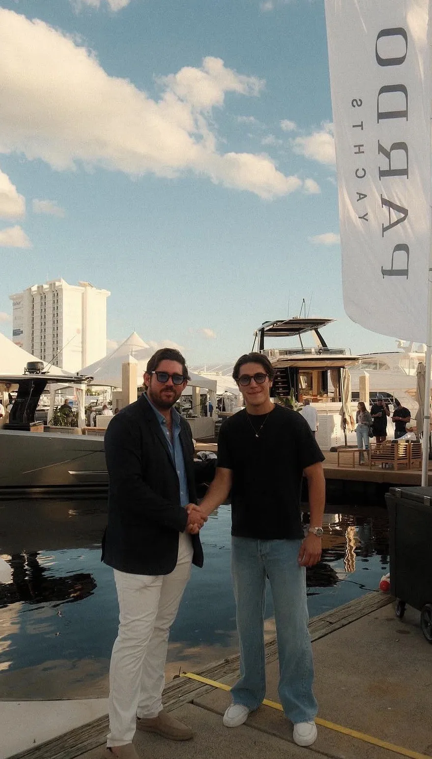 Gus Otaduy shaking hands with a colleague on the docks beneath a Pardo Yachts banner at the Fort Lauderdale boat show