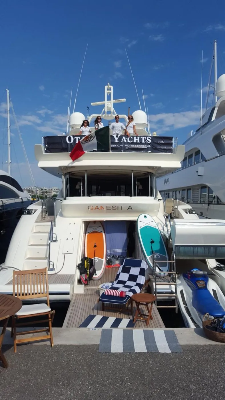 Crew in uniform on the flybridge of Ganesha at the Cannes Yachting Festival, beneath an Otaduy Yachts banner with the Mexican flag flying