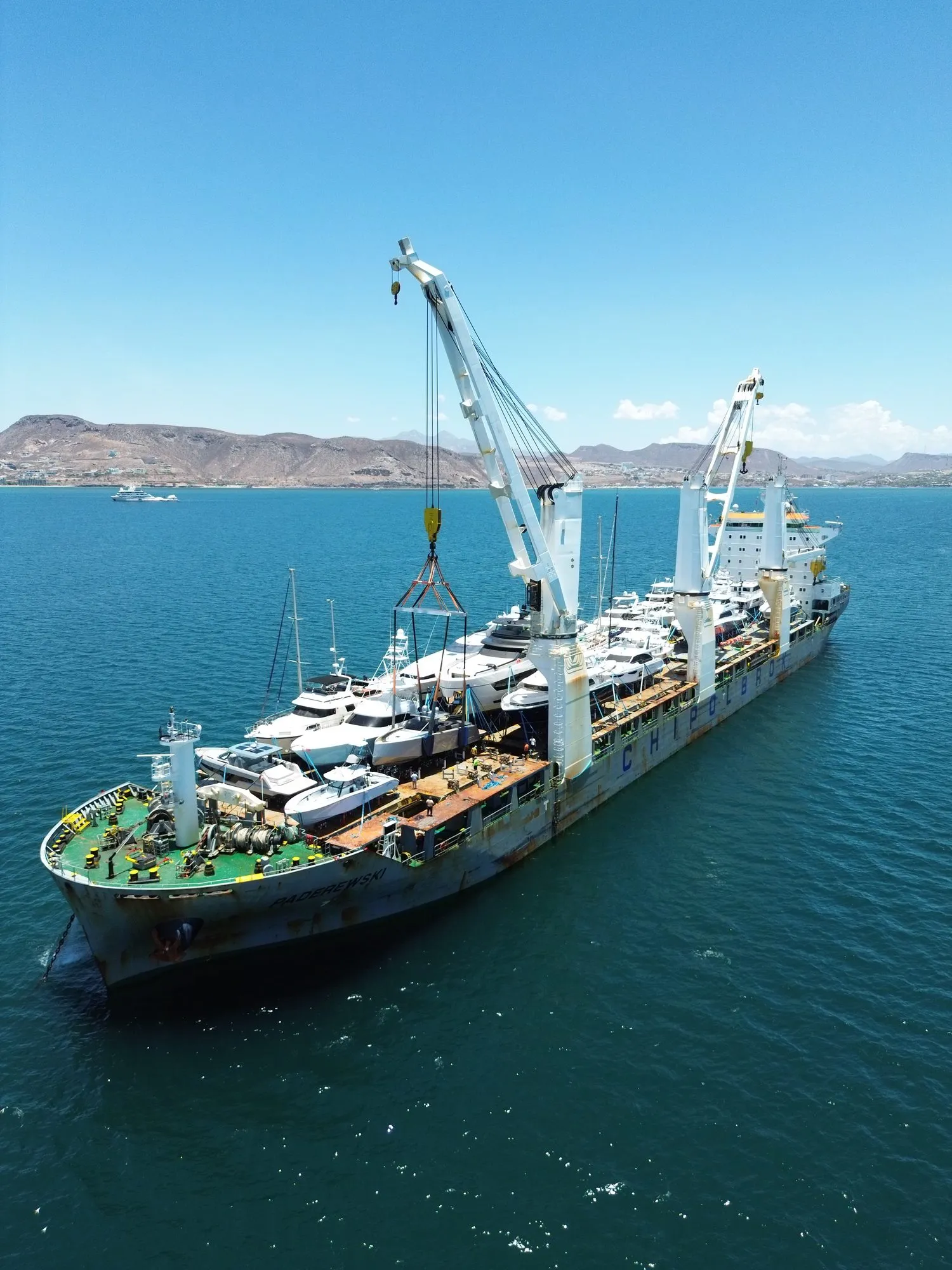 Transport ship carrying yachts along the Baja coast, aerial view