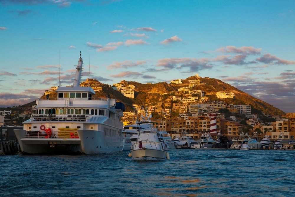 Superyacht going into the Cabo San Lucas Marina as the sun sets behind it.