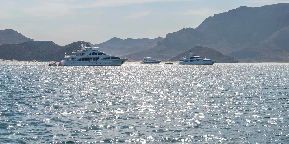 Superyachts sailing new La Paz on a clear day where the sun is shimmering off the water.