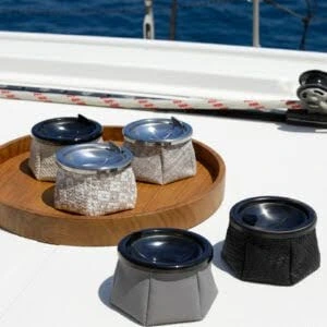 Marine Business ash trays on the yacht exterior. Three of which are on a wooden tray and two are sitting outside on the yacht.