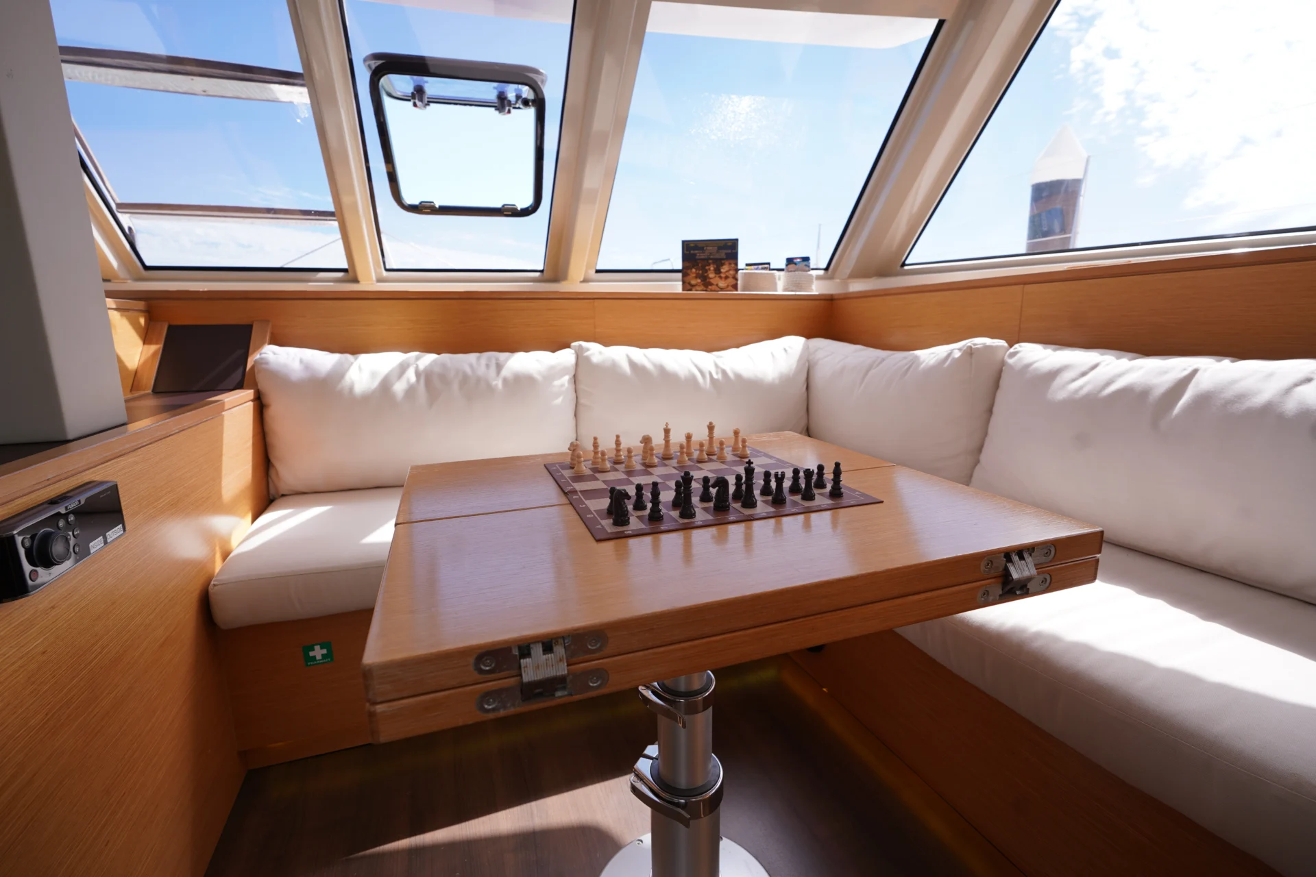 The interior of the sailing catamaran Telemachus, with white sofa and a chess board on the table.