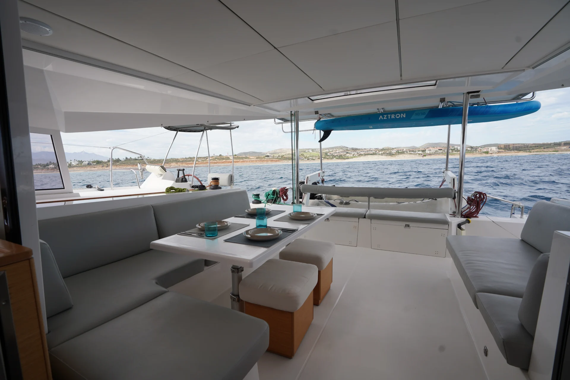 The exterior of the sailing catamaran Telemachus under awning with grey seating.